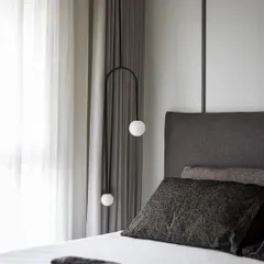 This calm and serene bedroom uses a soothing palette of soft greys and neutrals. The custom suspended light fixture adds a modern, sculptural element, while the plush bedding invites you to unwind.