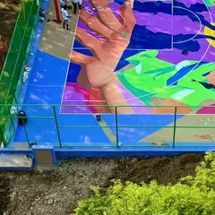 A section of the court mural coming to life, showing a hand reaching for a basketball. The design is a dynamic mix of abstract shapes and figurative elements.