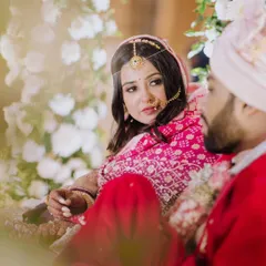 A quiet, candid moment between the bride and groom during their wedding ceremony. The bride's loving gaze towards her partner is framed beautifully by the floral decor.