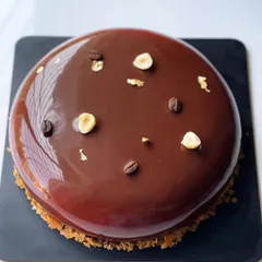 Another angle of the glossy, perfect glaze on the Coffee Hazelnut entremet, garnished simply with toasted hazelnuts and coffee beans.
