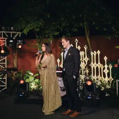 The happy couple addressing their guests. Styling a couple means ensuring their outfits work together on stage and off. His simple, well-fitted suit allows her glamorous saree to be the star.