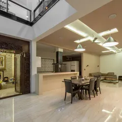 A seamless blend of modern living and traditional values in this Bangalore residence. The open-plan dining and kitchen area flows effortlessly, while the intricately carved wooden doors of the puja room stand as a beautiful, sacred focal point, grounding the contemporary design in cultural heritage.