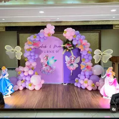 This fairy and princess-themed backdrop combines Disney princesses Cinderella and Aurora with fairy graphics and a pink and purple balloon arch.