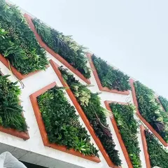 This exterior wall features a unique geometric design. I used wood-framed, diamond-shaped planters filled with various artificial plants to create a modular, 3D art piece.
