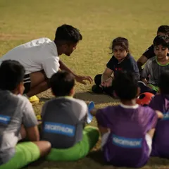 Coaching here is about more than just drills. A coach kneels down to connect with our youngest players, including a future Shewolf, explaining the importance of teamwork and strategy. We build players who are not just skilled, but also smart.
