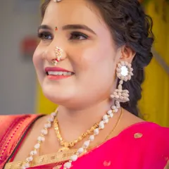 A close-up portrait of a bride, showcasing her beautiful smile and traditional jewelry. This shot focuses on her expressive face and the fine details of her Maharashtrian bridal look, including her nath and earrings.