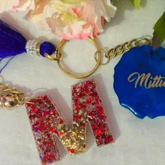 You can mix and match styles for a truly custom keychain. This set features a glittery initial 'M' paired with a solid blue charm personalized with the name 'Mittu'.
