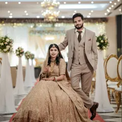 A grand portrait of the couple at their Walima reception, showcasing the bride's stunning gown and the elegant decor.