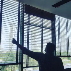 Here I am adjusting a newly installed set of wooden blinds. I handle the complete installation to ensure they fit perfectly and operate smoothly for light control and privacy.