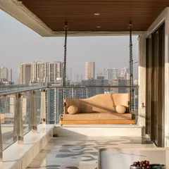 A high-rise sea-facing terrace designed for leisure, featuring a comfortable swing with an elegant, curved form. The terrazzo flooring adds a touch of modern craft.