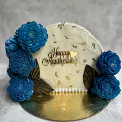 A beautiful top-forward cake for a wedding anniversary. This Belgian Chocolate cake is decorated with buttercream frosting, gold leaf, and stunning dried blue flowers for a modern yet elegant look.