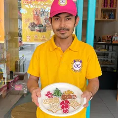 Our baker proudly presents a plate of freshly decorated Christmas cookies. These festive shapes, from gingerbread men to trees, are a crunchy, delicious treat for your dog.