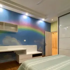 A dreamy bedroom scene with a custom rainbow and clouds mural, creating a cheerful and inspiring space for a child.