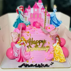 A fairytale princess cake featuring multiple Disney princesses and a castle topper.