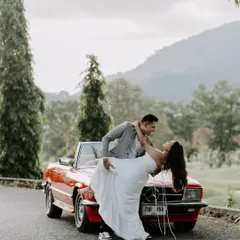 A classic romance scene with a vintage red Mercedes. This shot captures a timeless, movie-like dip against the beautiful hills of Thailand, showing our love for creating iconic, romantic pre-wedding photographs.