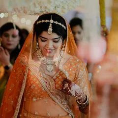Reeya walked down the aisle for her beautiful sunset Varmala in this gorgeous orange lehenga. We paired it with a fresh matte face, copper-hued eyes, and blooms in her bun that matched her outfit, creating a stunning Marwadi bridal look.