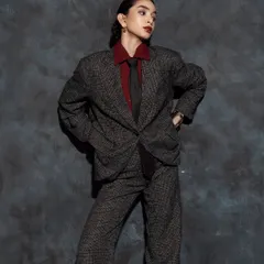 The androgynous styling is complemented by a strong yet clean makeup look, focusing on flawless skin and a statement lip.
