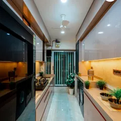This galley kitchen is designed for maximum efficiency. The glossy beige cabinets and under-cabinet lighting make the narrow space feel bright and open, with dedicated spots for all appliances.
