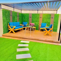 Imagine your terrace as the perfect spot for a sunny weekend brunch. We created this vibrant outdoor lounge with comfortable seating, durable artificial turf, and a signature green wall accented with wood panels, all under a modern pergola.