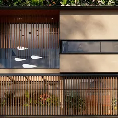 A closer view of the facade details on the 18th Avenue House. The vertical wooden louvers provide privacy and filter the harsh sun, while the glass balcony with subtle motifs adds a touch of modern artistry to the tropical design.