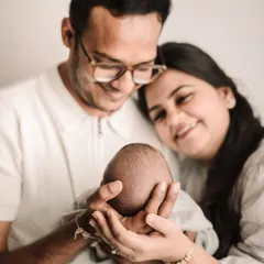 A close-up shot focusing on the parents' hands cradling their newborn's head, a symbol of protection and love.