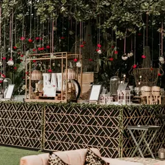 An elegant outdoor bar setup perfect for a sophisticated evening reception. The geometric bar front, combined with hanging floral decor and warm lighting, creates a chic and inviting space for guests.