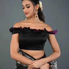 An elegant off-the-shoulder blouse in black satin with a delicate purple ruffle. This design is perfect for evening events and cocktail parties.