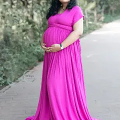 A classic and elegant maternity portrait. The flowing pink gown and the gentle way she holds her bump create a timeless image of a mother's love.