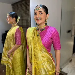 A full-length view showing Archi's complete look. The sleek bun adorned with flowers and the elegantly draped saree create a look of classic, traditional beauty.