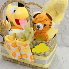 A close-up of the "Little Bundle of Sunshine" hamper. This shot highlights the hand-knitted tiger toy and the cute lion-print booties, showing the mix of handmade and classic items.