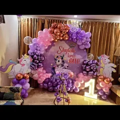 A magical unicorn-themed first birthday party for Shylah. I used shades of purple and pink for the balloon arch and included unicorn cutouts, a custom backdrop, and a light-up number '1'.
