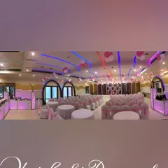 A panoramic view of a fully decorated hall. This shows how I coordinate everything from the chair covers and table settings to the ceiling decor and buffet counters to match the pink and white theme.