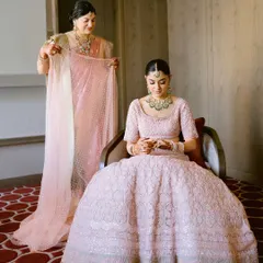 A mother helps her daughter with her dupatta, a quiet and touching moment of preparation before the wedding ceremony.