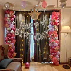 A close-up of the main decoration area for the Pinterest-inspired birthday. The two balloon pillars in shades of pink, purple, and silver frame the 'Happy Birthday' foil balloons and a cute crown, fit for a queen.