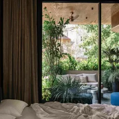 A view from a bedroom in Project 1374 looking out onto a private, plant-filled terrace. Large sliding glass doors dissolve the boundary, allowing the garden to become an extension of the living space.