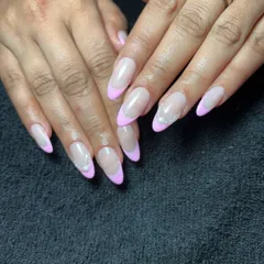 A soft and pretty French manicure with pastel pink tips on almond-shaped nails. Tiny pearl accents at the cuticle add a touch of simple elegance.