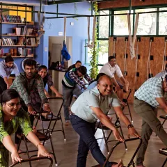 Employees at Health Heal engage in a chair-based stretching exercise. These simple movements are designed to be done in office attire, breaking the monotony of sitting and improving circulation.