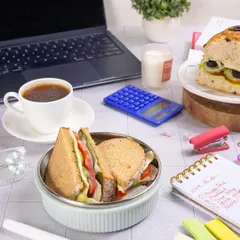 A realistic "desk lunch" scene, featuring a healthy sandwich and coffee to fuel a productive workday.