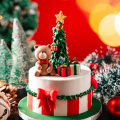 This Christmas cake is pure festive cheer. It features a classic red and white striped base, a green bow, and is topped with a handcrafted teddy bear and Christmas tree, all made from fondant.