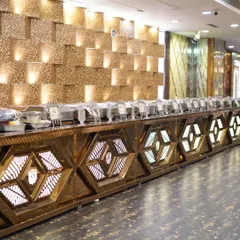 The lavish food buffet setup at a grand event. The golden, illuminated counter and extensive spread are a feast for the eyes.
