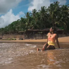 A candid shot from the same beach session in Goa. This photo captures a moment of peaceful reflection against the backdrop of palm trees and the open sea.