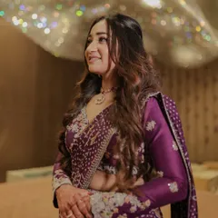 A portrait of the bride-to-be, Hinal, during her virtual engagement. Her radiant smile and the stunning details of her purple outfit are beautifully captured under the sparkling lights.