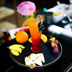 A classic layered mocktail with orange and grenadine, garnished with a fruit skewer and a fun umbrella. A tropical delight for all ages.