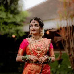 A stunning portrait of the bride in her magnificent red and pink Kanjivaram saree, adorned with traditional gold jewelry. She embodies the grace and elegance of a South Indian bride.