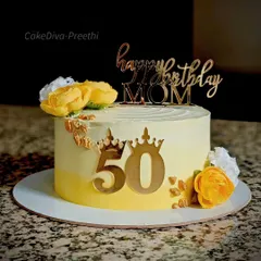 A sunny and cheerful cake for a mom's 50th birthday. The yellow ombre buttercream is decorated with golden accents, a custom topper, and beautiful yellow and white sugar flowers.