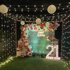 Celebrating a 21st birthday with a glamorous terrace decoration. This setup features a sparkling shimmer wall, a neon 'Happy Birthday' sign, marquee numbers, and a canopy of fairy lights to create a stunning nighttime ambiance.