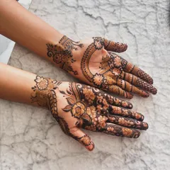 This Pinterest-inspired design combines two different styles. One hand has a large floral vine pattern, while the other features a crescent moon shape, both popular in modern designer mehndi.