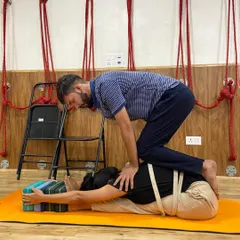 I believe in a hands-on approach to ensure you are safe and getting the most out of every posture. Here, I'm assisting a student in a supported forward bend, using a chair, blocks, and straps to deepen the stretch without any strain on the back.