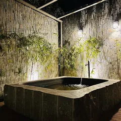 The feature is fully functional, with a discreet water inlet that creates a gentle flow, enhancing the sense of peace and tranquility. The surrounding wooden deck and stone walls complete the authentic Japanese garden aesthetic.