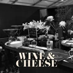 A chic and moody shot of a wine and cheese station, perfect for a corporate networking event. The black and white photo emphasizes the elegant lines and sophisticated atmosphere.